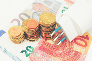 Electric plug with money and coins. Energy saving concept. Soft and selective focus.