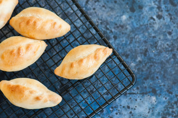 Small mashed potato pasties (hand pies) in a wire rack. Blue stone background.