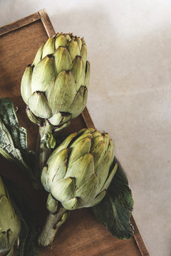 Overhead view of artichokes with leaves on wooden table