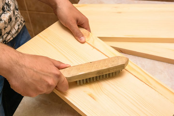 Hand with brush brushes wooden plank