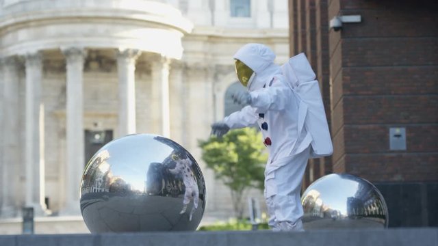  Funny astronaut returned to earth, trying to pick up a metal sphere sculpture