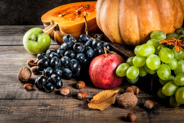 Autumn and thanksgiving harvest concept. Seasonal fall fruits and pumpkin on wooden table, copy space