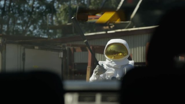  Aggressive astronaut with road rage approaching car swinging a baseball bat.