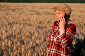 Female farmer in wheat field talking on mobile phone