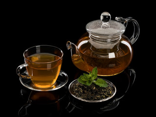 Tea leaves of green tea with petals of fresh mint and a tea drink in glassware