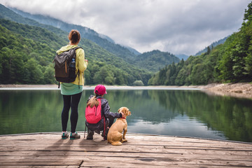Mother and daughter standing on the pier with a dog