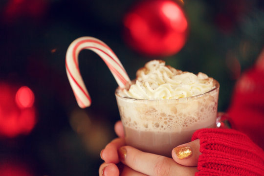 Girl holding cacao with whipped cream and peppermint candy cane. Christmas holiday concept. Holiday background