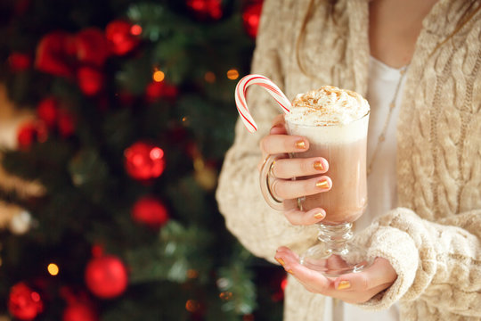 Girl holding cacao with whipped cream and peppermint candy cane. Christmas holiday concept. Holiday background