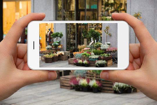 Woman take photo of street flovers market by phone.