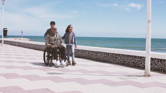 Ni&ntilde;os empujando la silla de ruedas de su abuelo