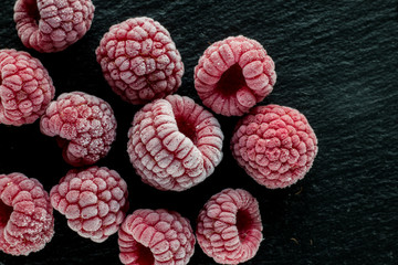 frozen raspberry on black slate background, macro, top view