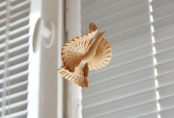 Wooden bird on a background of white blinds