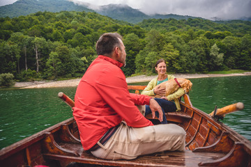 Couple with a dog rowing a boat on a lake