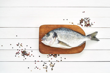 Fresh dorado fish on wooden cutting board with garlic. Top view, copy space