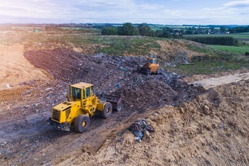 Aerial view on bulldozers working on the landfill.