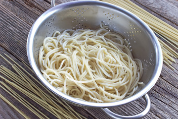 Cooked spaghetti pasta in strainer on wooden table