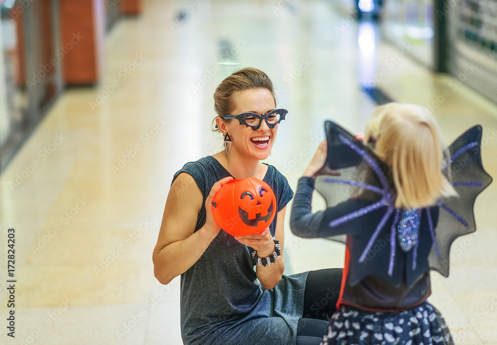 Sticker smiling modern mother and daughter on Halloween at mall playing