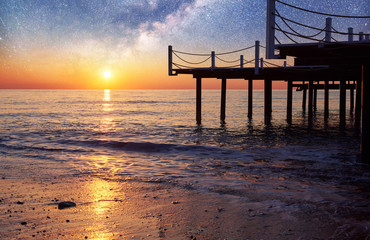 Fantastic starry sky and the Milky Way to the pier at sea, used to natural background sea. Romantic...