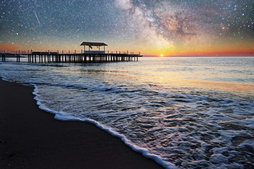 Fantastic starry sky and the Milky Way to the pier at sea, used to natural background sea. Romantic...
