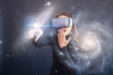 Young beautiful girl gets positive emotions using virtual reality goggles. A woman examines star...