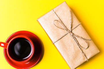 Red Cup with coffee and gift on yellow background