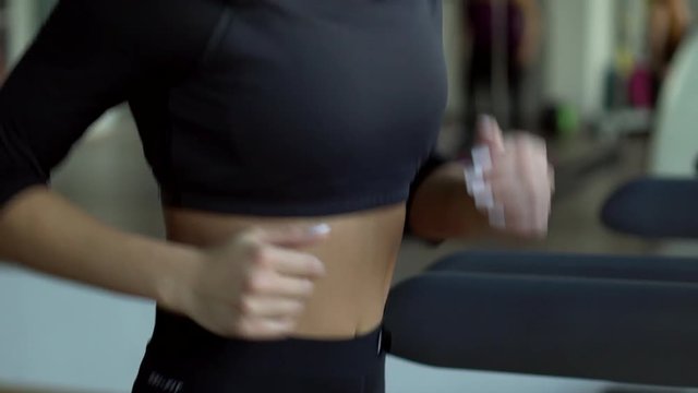 young woman runs on a treadmill in the gym, slow motion, close-up
