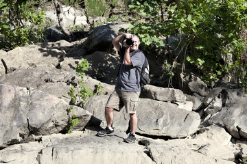 Photographer on Rocks Aims Camera at Viewer