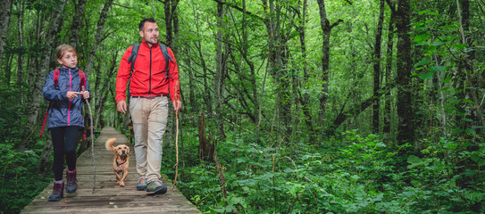 Father and daughter with a dog hiking in the forest