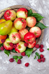 Fresh raspberries and apples on old wooden plate on a concrete background. Healthy concept. Natural healthy food. Organic food.