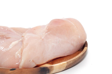 raw chicken breast on wooden plate on white background