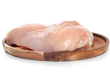 raw chicken breast on wooden plate on white background