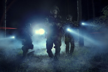 Fototapeta na wymiar Special Forces soldiers in action. Elite squad moves through fog and smoke.