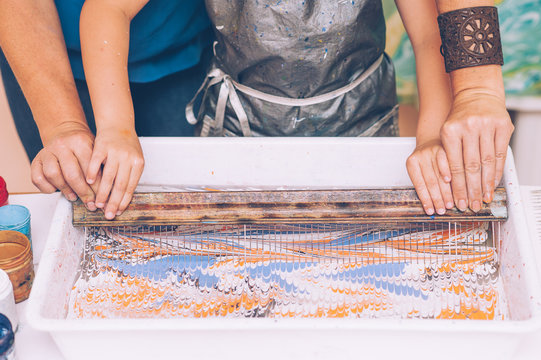 Master teaches a little girl the technique of ebru