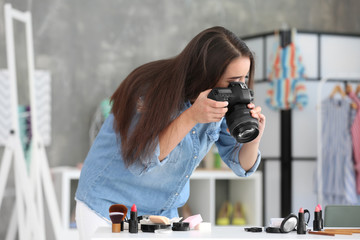 Young female blogger making photo of cosmetics at home