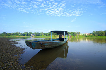 Old Blue boat nearby a river at beautiful summer sunrise
