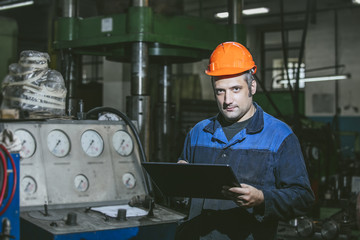 Working in the plant with tablet in hands on the background of the equipment