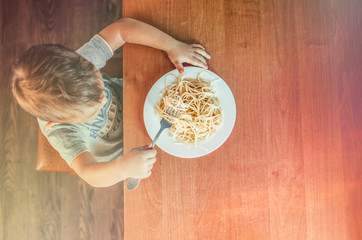The child at the table eating macaroni and interesting angle