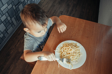 The child at the table eating macaroni and interesting angle