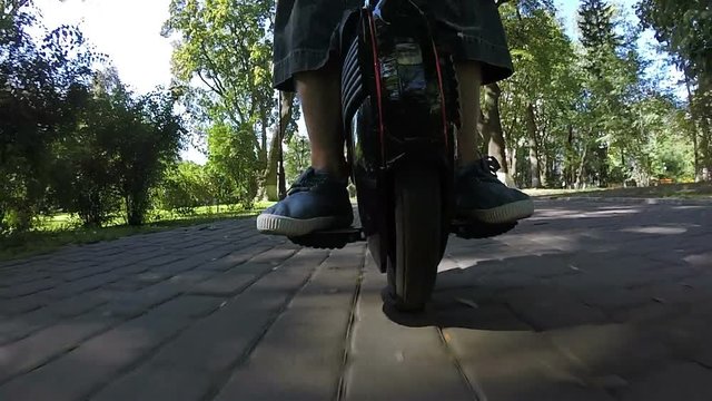 
Mono wheel in city park with feet of rider Sunny day. POV view
