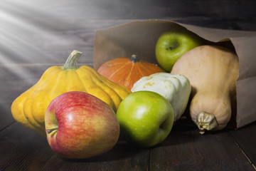 Autumn vegetables under the sun in the basement. Pumpkins, apples, squash, autumn leaves on a wooden table. Harvest.