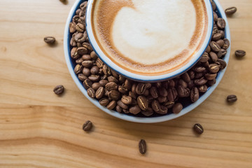 Coffee background with a cup of cappuccino and fresh roasted Arabica beans.