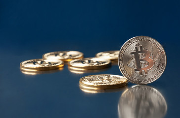 A few gold coins bitcoin lie on a blue background. The concept of crypto currency