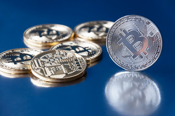 A few gold and silver   coins bitcoin lie on a blue backgroundConcept of crypto currency