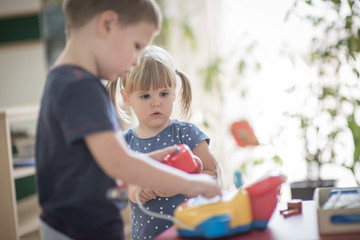 Obraz premium Brother showing sister how to play with toy