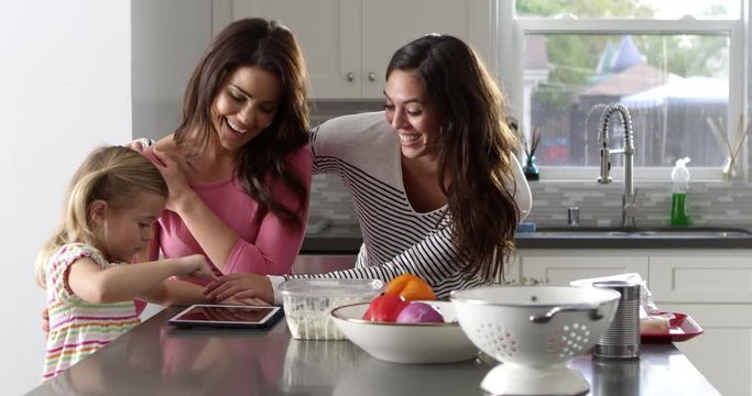 Female parents with daughter looking at tablet in their kitchen, shot on R3D