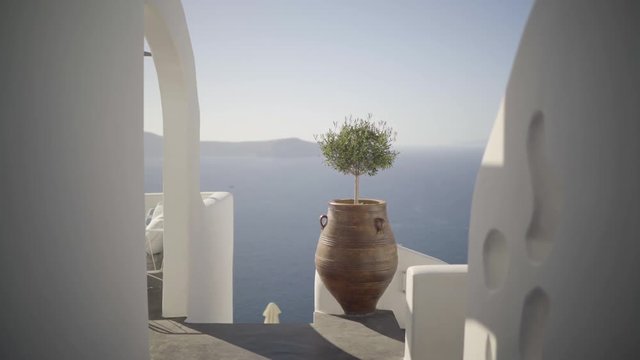 4k travel video dolly move in path between white greek walls in santorini facing sea and caldera
