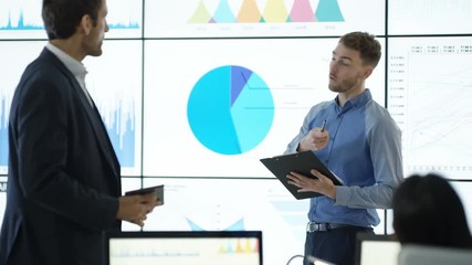  Business team in a meeting, discussing financial charts & graphs on video wall