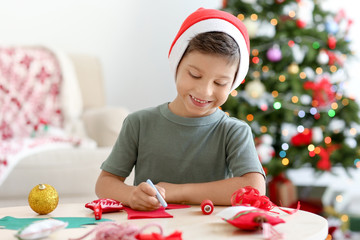 Cute boy making Christmas sock from felt on table