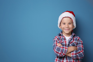 Cute boy in Santa hat on color background