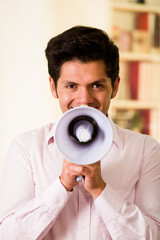 Close up of a handsome man screaming with a megaphone in a blurred background